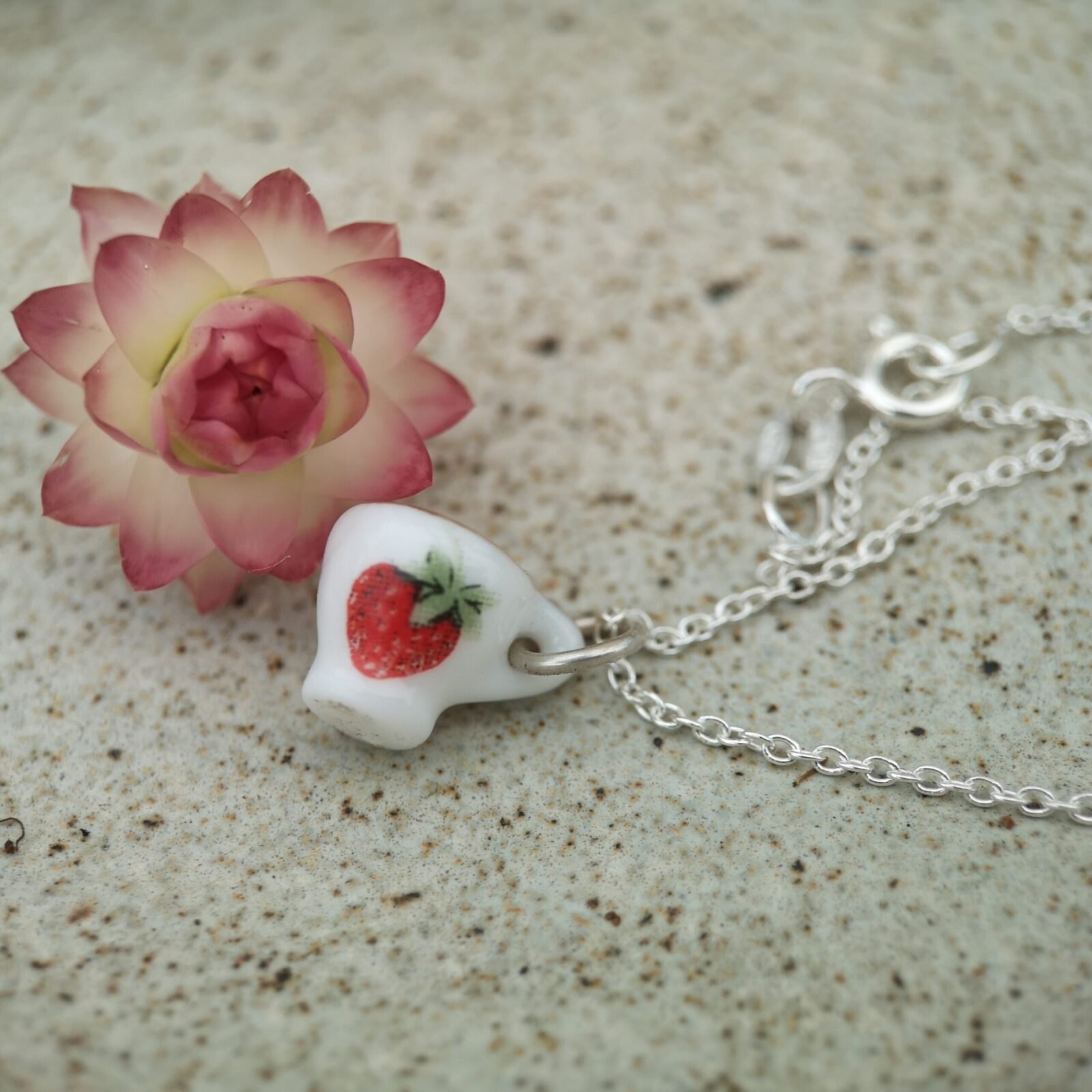 Whimsy Tiny porcelain tea cup with a strawberry and a gold rim hanging on a silver chain necklace