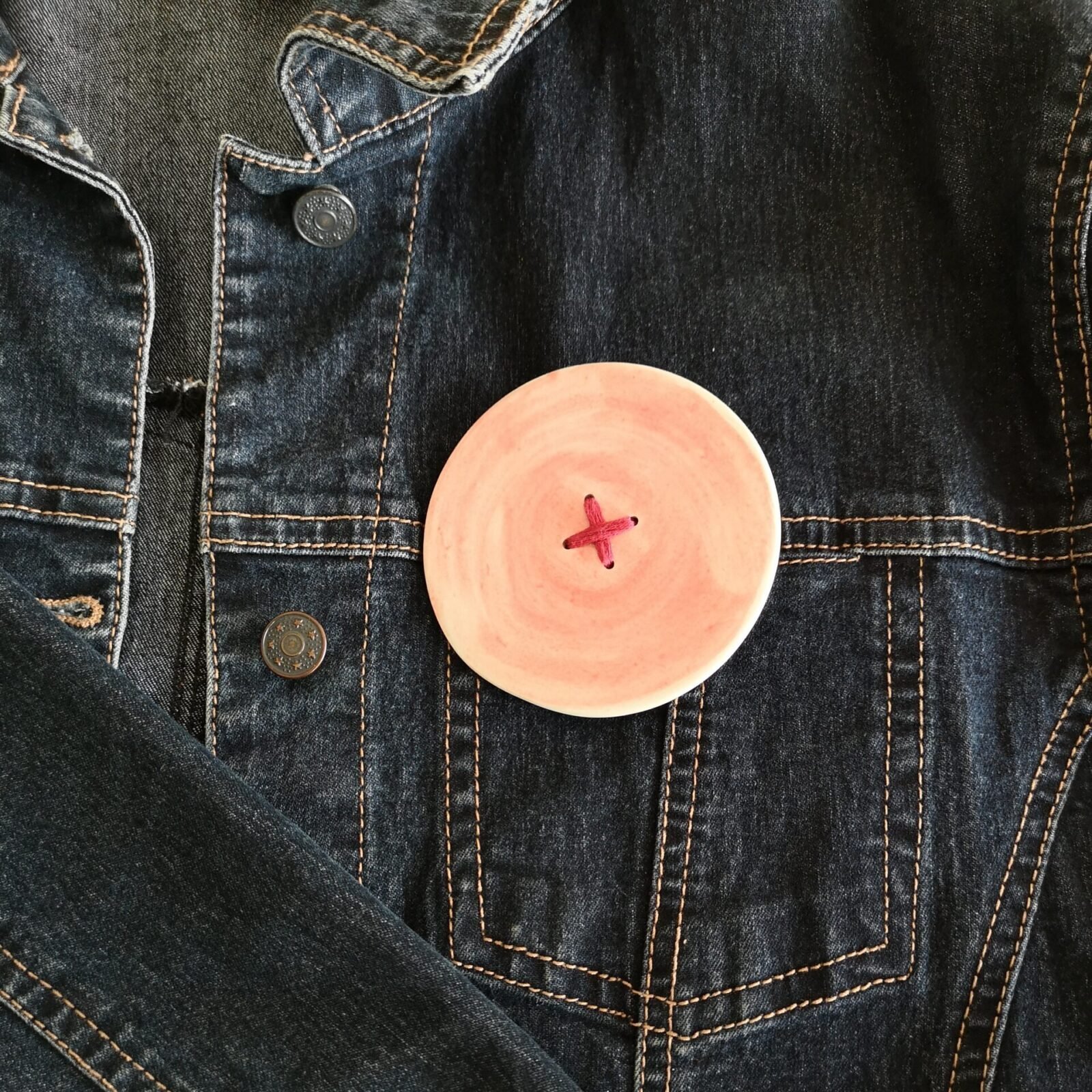 big red button brooch with red stitching details